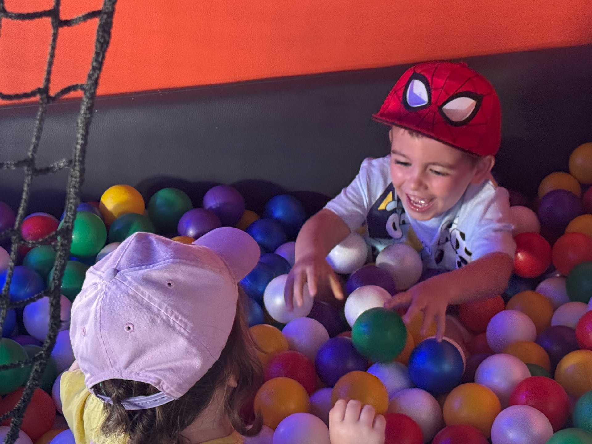 Two children playing together in a colourful ball pit inside the mobile sensory room.