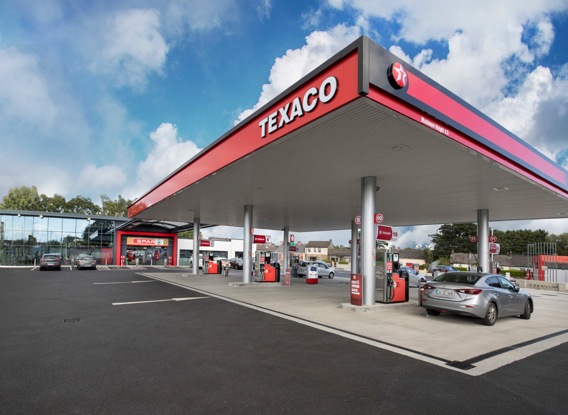 A Texaco service station forecourt and canopy with the shop alongside on a bright day.