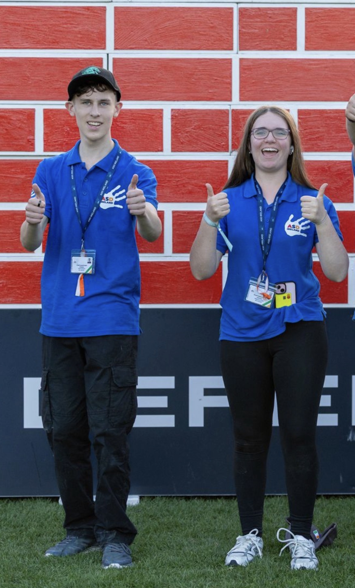 Two ASD Ireland volunteers in blue polo shirts giving a thumbs up at an event.