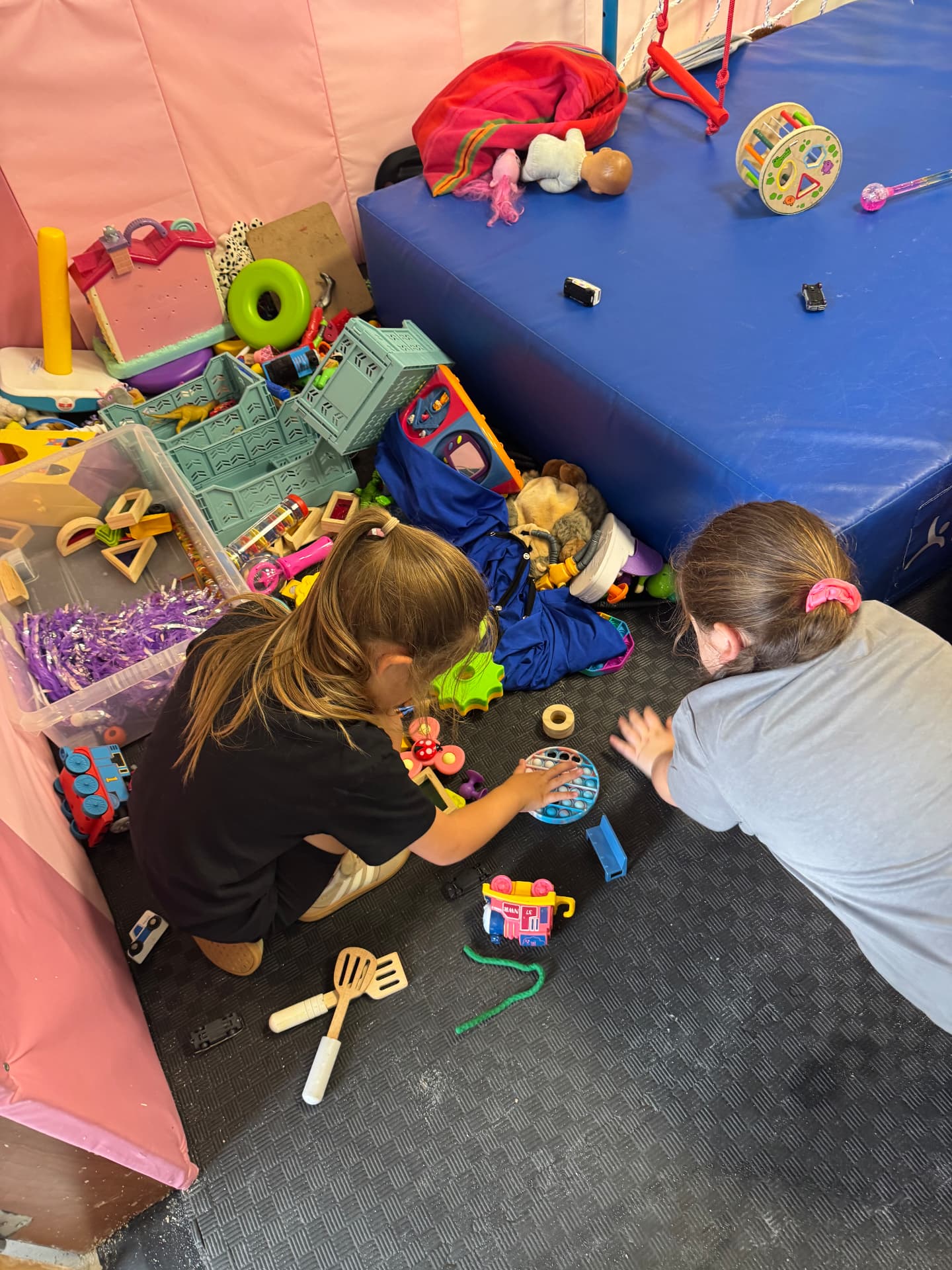 Two girls playing with sensory toys on soft flooring at the ASD Ireland summer camp.